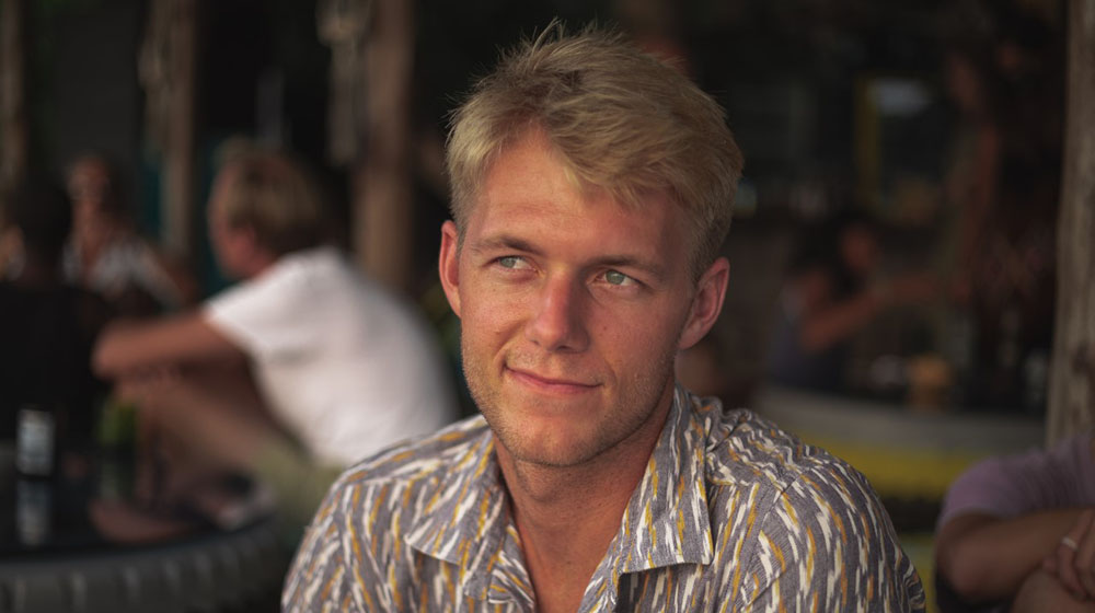 Alex Stoll sitting in an outdoor lounge, looking into the distance